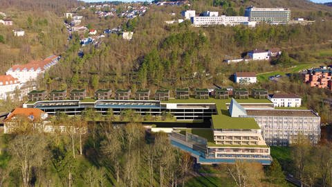 „MediSpa Gesamtansicht“: In nachhaltiger Bauweise, ausgehend vom sanierten Parkhotel und mit viel Holz und Grün fügt sich MediSpa mit Dachterrasse, Chalets, Parkdecks und kleinen Lodges harmonisch in den Hang oberhalb des Kurparks ein. Das jetzige Betriebsgebäude mit Abfüllanlage, Heizwerk und Schornstein verschwindet. 