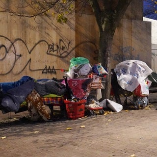 Zwei obdachlose Mesnchen schlafen umgeben von ihrem Hab und Gut auf Bänken unter einer Brücke