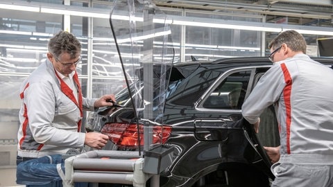 Zwei Männer arbeiten in eienr Halle an einem Auto