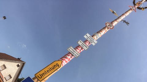 Der Maibaum ist mit Baustellenschildern geschmückt