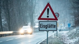 Ein Schild mit Eisglätte am Straßenrand