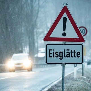 Ein Schild mit Eisglätte am Straßenrand