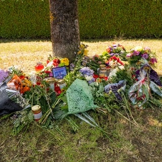 Blumen, Kerzen und Bilder liegen an einem Baum, in dessen Nähe am 17.August 2022 eine 23-Jährige aus dem Kreis Heilbronn tot in einem Auto entdeckt wurde.