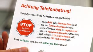 Karte mit der Aufschrift "Achtung Telefonbetrug!" und weiteren Warnhinweisen