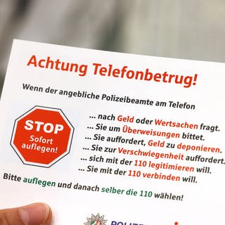 Karte mit der Aufschrift "Achtung Telefonbetrug!" und weiteren Warnhinweisen