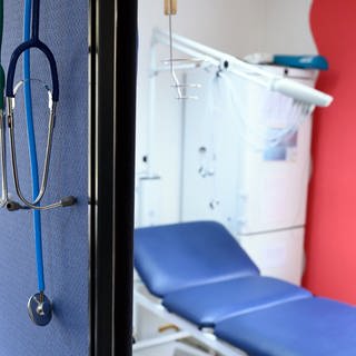 Stethoskope hängen im Behandlungszimmer einer Hausarztpraxis über einer Trennwand.