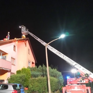 Die Feuerwehr repariert mit Drehleitern notdürftig Dächer mit Planen