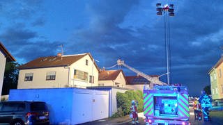 Die Feuerwehr repariert mit Drehleitern notdürftig Dächer mit Planen