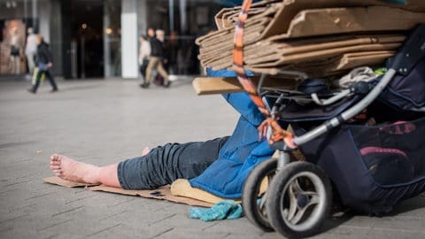 Ein Obdachloser liegt barfuß in der Innenstadt (Symbolbild)