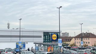 Preissenkung bei Lidl für Fleischersatz: Zu sehen ist der Parklpatz einer Lidl-Filiale. Im Hintergrund ist der Supermarkt zu sehen und das gelb-blau-rote Lidl-Schild.