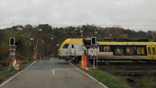 Am Bahnübergang in Grünsfeld ist die Bahnschranke trotz durchfahrenden Zuges nicht geschlossen. Blick aus haltendem Pkw.