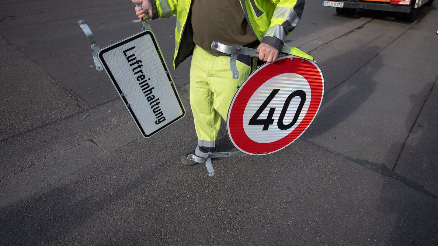 Symbolbild: Ein Mann trägt ein Tempo 40 Schild und ein Schild mit der Aufschrift 