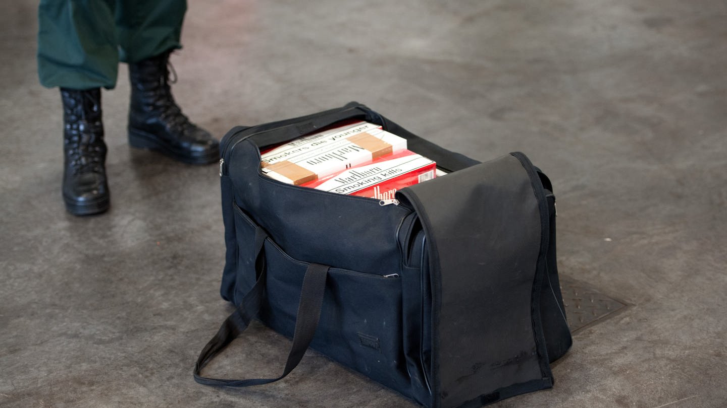 Ein Zollbeamter steht neben einer Tasche mit geschmuggelten Zigaretten (Symbolbild).