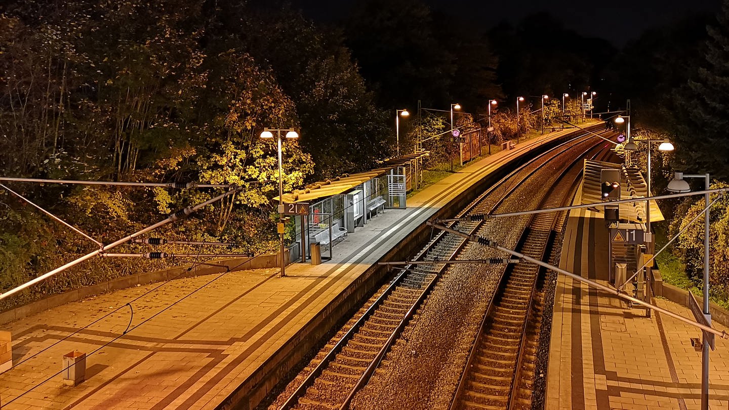 Bahnlinie mit Haltestelle, nachts. Symbolbild.