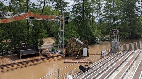 Die Bühne der Gruppe Theater im Fluss steht im Wasser. Helfer waten durchs Wasser.