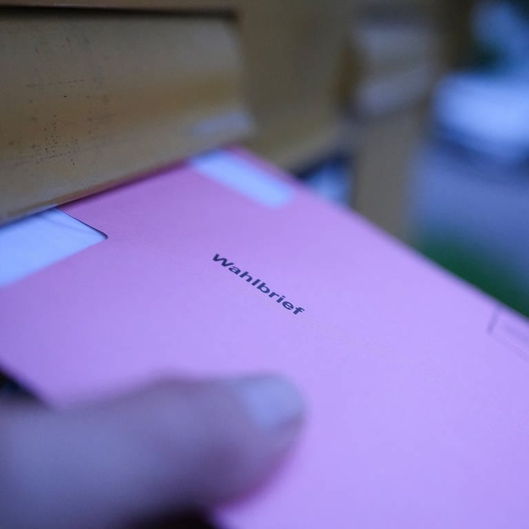 Stimmzettel werden in einen Briefkasten geworfen