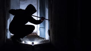 Einbrecher steigt mit Brecheisen in Gebäude ein. Symbolbild zu Einbruch in Schwäbisch Hall