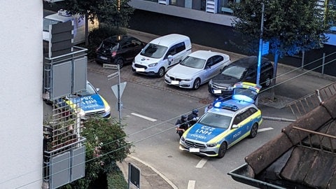 Polizeieinsatzkräfte gehen in Deckung hinter einem Einsatzfahrzeug. Ein Mann wurde nahe des Heilbronner Landratsamts in seiner Wohnung vorläufig festgenommen. 