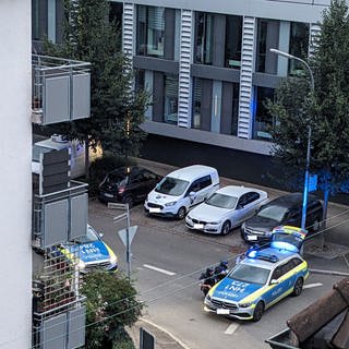 Polizeieinsatzkräfte gehen in Deckung hinter einem Einsatzfahrzeug. Ein Mann wurde nahe des Heilbronner Landratsamts in seiner Wohnung vorläufig festgenommen. 