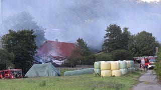 Feuerwehrleute löschen einen Brand an einem landwirtschaftlichen Anwesen in Forchtenberg-Ernsbach. 