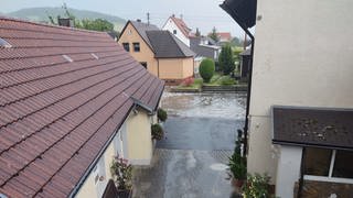 Wasser steht nach starken Regenfällen auf einer Straße in Unterbalbach