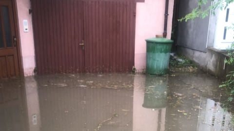 Wasser steht nach einem Unwetter vor einem Hauseingang in Unterbalbach