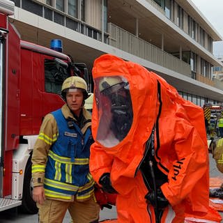 Ein Feuerwehrmann legt einen Schutzanzug an.