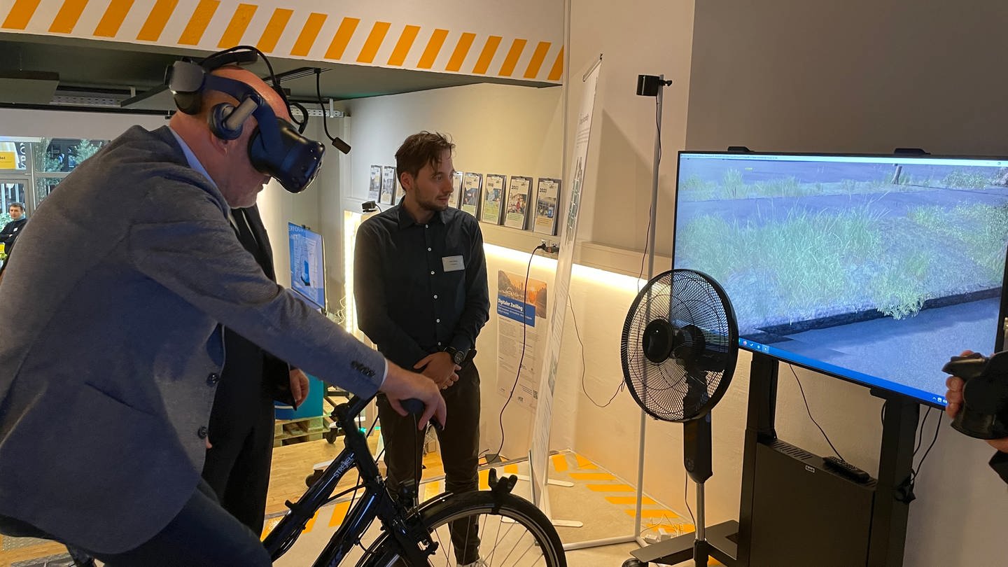 Verkehrsminister Winfried Hermann (Grüne) auf einem Fahrrad, mit dem per KI das Verhalten der Fahrer analysiert wird.