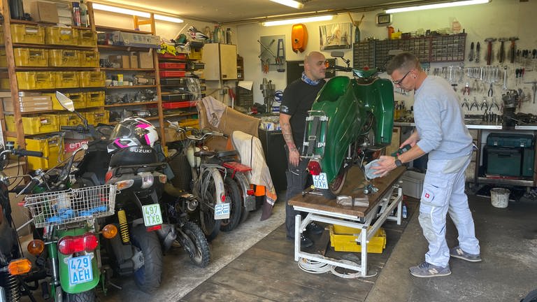 Zwar verstehe er nichts von Rollern, sagt Kunde Marco Ahlgrimm (rechts). Doch er packt bei der Reparatur seines Schätzchens gern mit an.