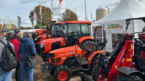 Muswiesenbesucher betrachten landwirtschaftliche Maschinen.