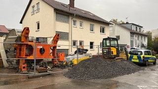 Ein Kran liegt vor einem Haus, er ist auf eine Garage gekracht. Die Polizei ermittelt