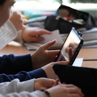 Schülerinnen und Schüler üben mit einem KI-Tool auf einem Tablet im Unterricht.