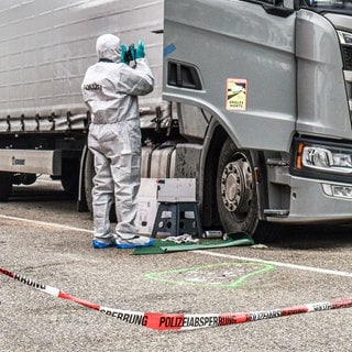 Ein Beamter der Spurensicherung arbeitet am Tatort auf einem Parkplatz in einem Industriegebiet im Kreis Schwäbisch Hall. Nach einer tödlichen Schlägerei zwischen vier Lastwagenfahrern in Baden-Württemberg wird gegen zwei der Trucker wegen gemeinschaftlichen Totschlags ermittelt.