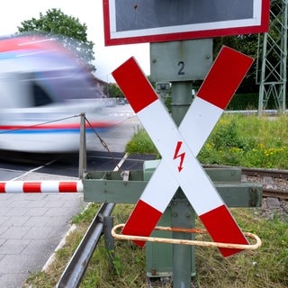 Ein Zug fährt an einer geschlossenen Bahnschranke vorbei (Symbolbild). Am Bahnübergang in Lauda-Königshofen wurde ein Pkw von einem Zug erfasst. 