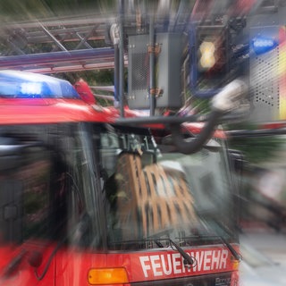 Ein Einsatzfahrzeug der Feuerwehr mit Drehleiter und Blaulicht mit Effekt-Überlagerung Symbolbild