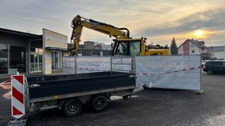 Der Tatort in Tauberbischofsheim am Tag nach der Bagger-Zerstörungsfahrt. Die Polizei hat den Ort, wo der Mann erschossen wurde, mit Sichtschutz, Flatterband und Anhängern abesperrt.