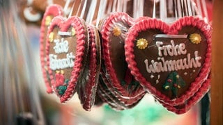 Lebkuchenherzen mit der Aufschrift "Frohe Weihnacht" hängen an einem Weihnachtsmarkt-Stand