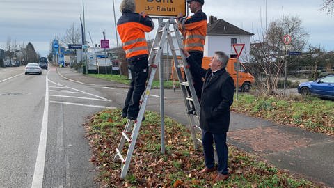 Unter den Augen von Oberbürgermeister Hubert Schnurr haben Mitarbeiter des Stadtbauhofs eine der neuen Ortstafeln montiert