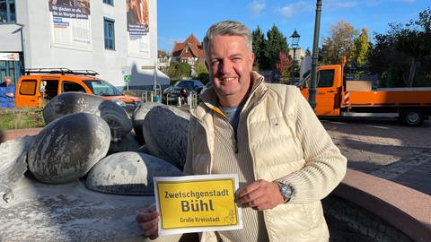 Michael Vetter von der Bürgerinitiative Bühl wirbt mit einem Plakat für den Titel "Zwetschgenstadt"