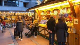 Die ersten Besucher stehen an den Buden auf dem Weihnachtsmarkt 2022 in Pforzheim.