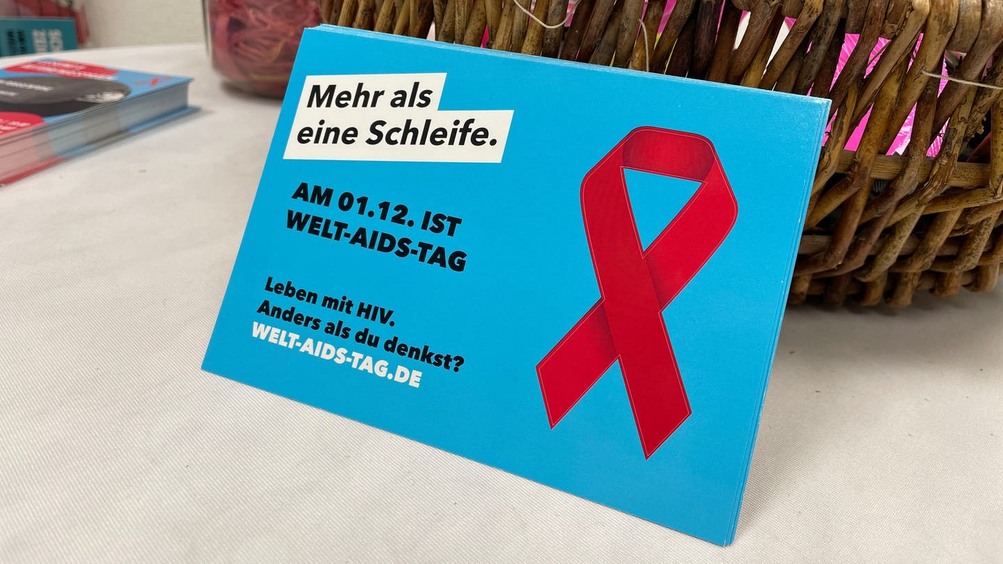Plakat mit roter AIDS-Solidaritäts-Schleife und der Aufschrift: 