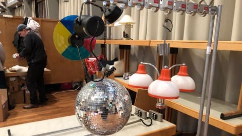 Eine Disco-Kugel und Lampen hängen an einem Kleiderständer