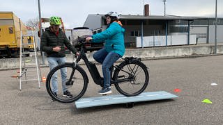 E-Bike-Fahrerin bekommt auf einem Parkplatz Fahrsicherheitstraining: Sie muss einen Parcours fahren.