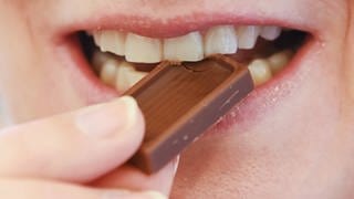 Eine Frau beißt genüsslich in ein Stück Schokolade