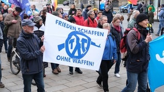 Demonstration für Frieden - mit einem Banner: Frieden schaffen, ohne Waffen - Tag der Kriegsdienstverweigerung