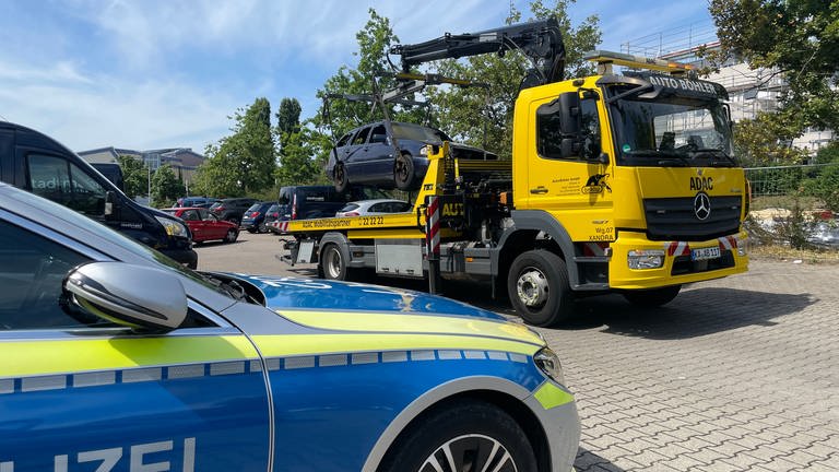 Ein Abschleppdienst lädt ein ausgebranntes Auto in der Karlsruher Waldstadt auf