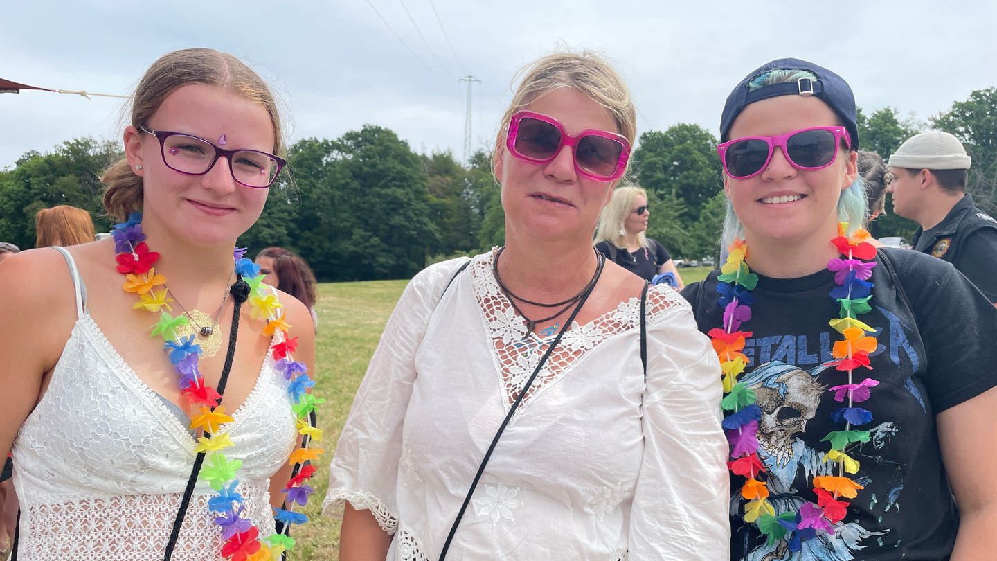 Drei Besucherinnen des Happiness-Festivals in Straubenhardt tragen pinke Sonnenbrillen und bunte Blumenketten