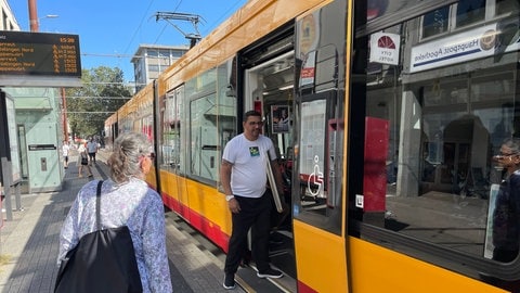 Straßenbahnen und S-Bahnen fahren in Karlsruhe, Leute an der Haltestelle steigen ein