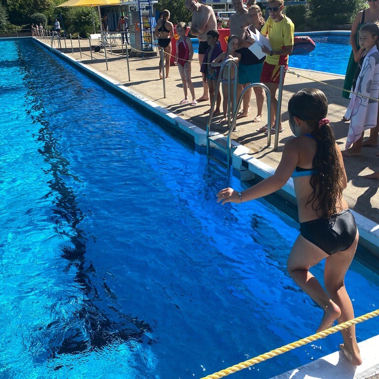 Schwimmkurs für Kinder im Wartbergbad in Pforzheim - ein Mädchen springt ins Becken, Badegäste schauen vom Beckenrand zu