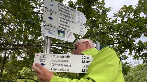 Ein Mann montiert Wegeschilder für die Wanderwege im Schwarzwald. Beim Wandern sollte man dennoch eine Karte dabei haben.